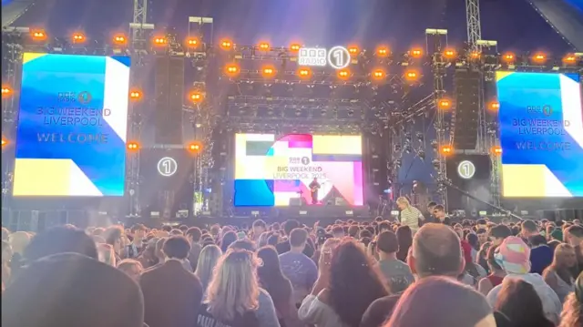 A stage packed with a huge crowd in front of it