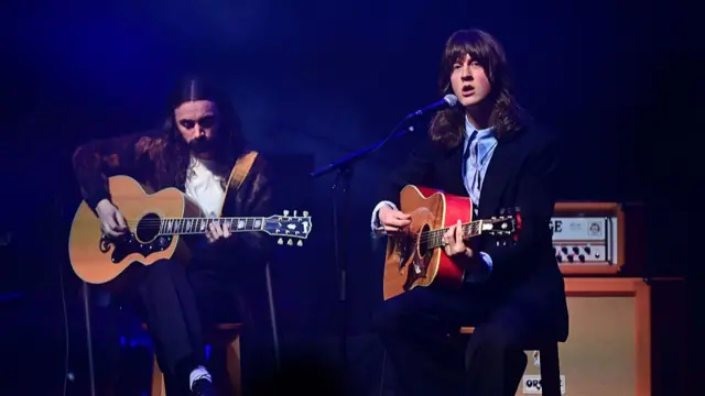 Blossoms band on stage playing guitars.