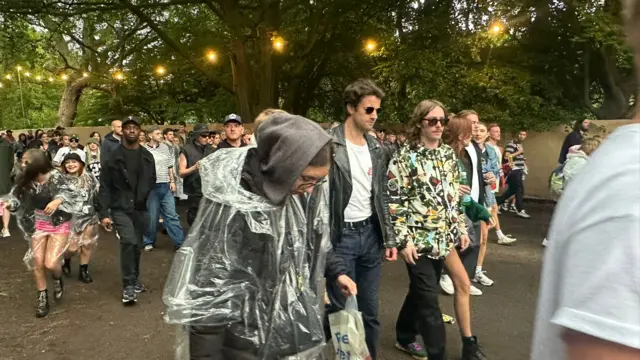 People in coats and ponchos walking along.