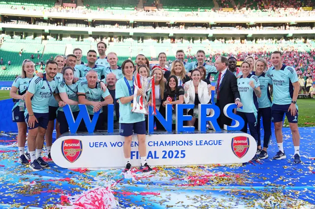 Slegers poses with the trophy alongside her staff