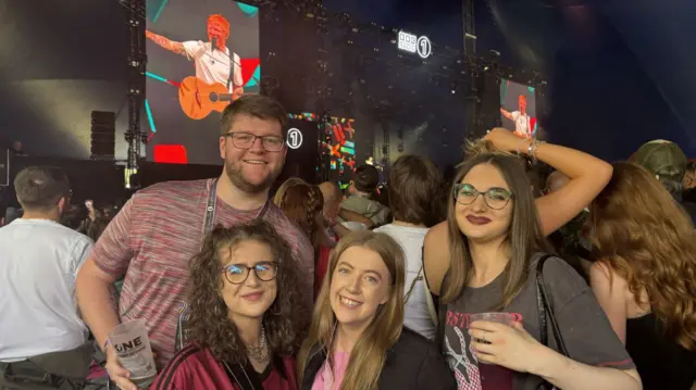 A group of people smile at the camera with the stage behind them