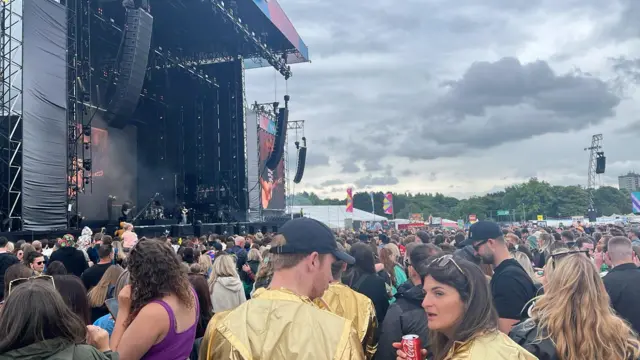 people wearing yellow ponchos gather in front of the main stage