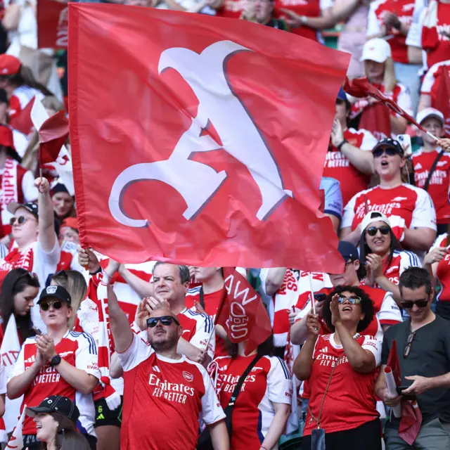 Arsenal fans wave a flag with an A on it