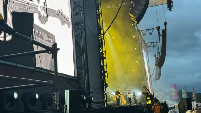 Sam Fender performs on the Main Stage. The picture is taken looking at the stage from the side.