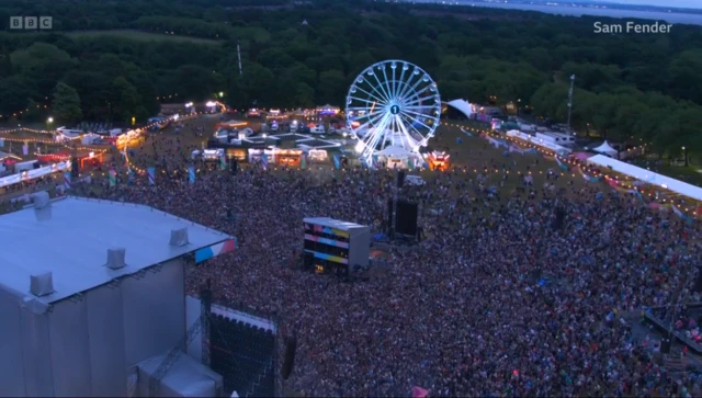 A huge crowd in front of a stage, aerial view.