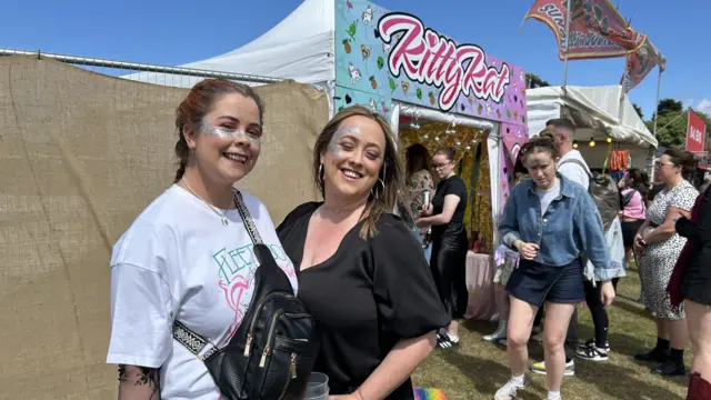 Sisters Aoife and Niamh Harvey smile at the camera. They both have green and white glitter on there face.