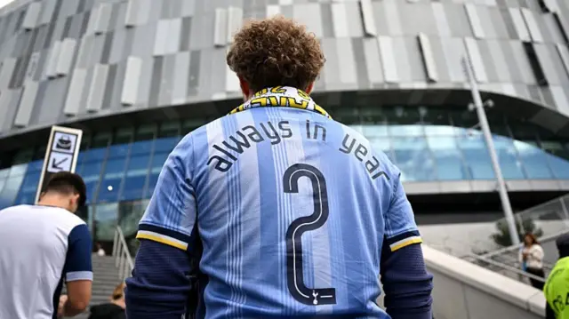 A Spurs fan outside the Tottenham Hotspur Stadium with 'always in year two' on his shirt