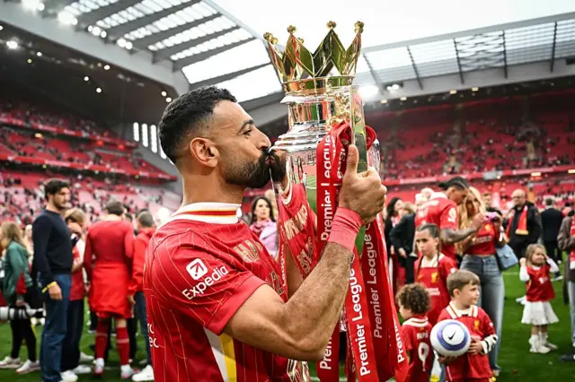 Liverpool's Egyptian striker #11 Mohamed Salah celebrates as he kisses the Premier League trophy