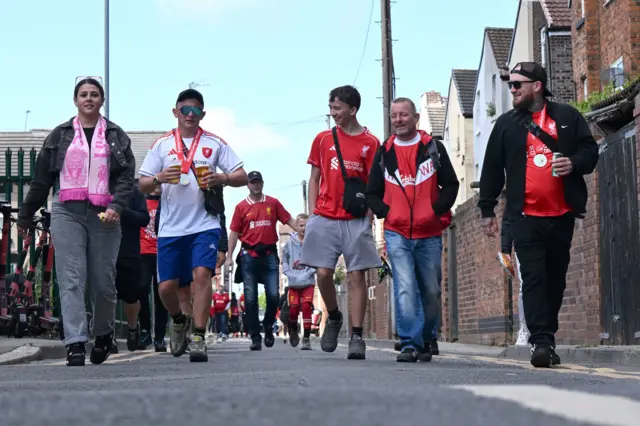 Liverpool fans, wearing their club's red colours, arrive at Anfield