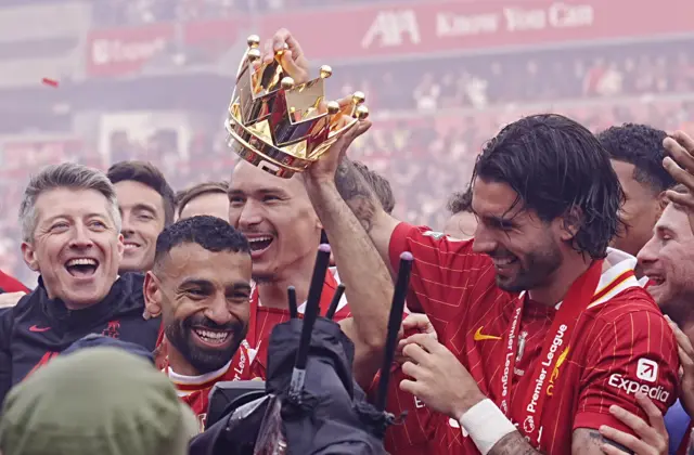 Mohamed Salah grins as team-mates place a crown (from the top of the Premier League trophy!) on his head