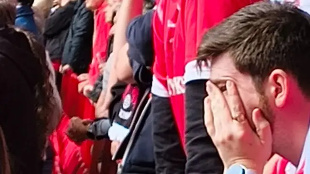 An Orient fan with their head in their hands