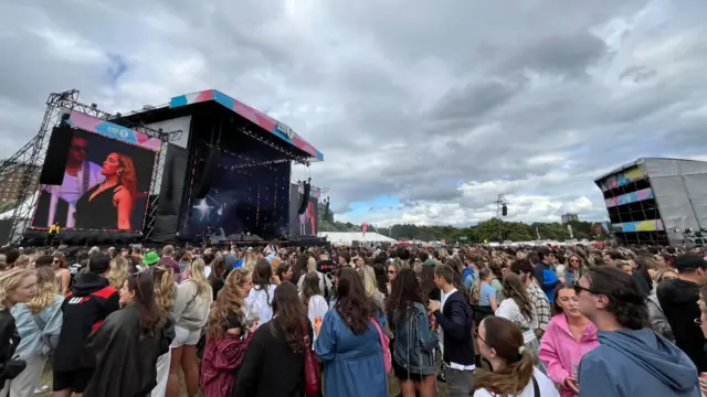 A wide shot of the stage where Jorja Smith is performing. There's a large crowd and a screen showing the singer. The skies are grey.