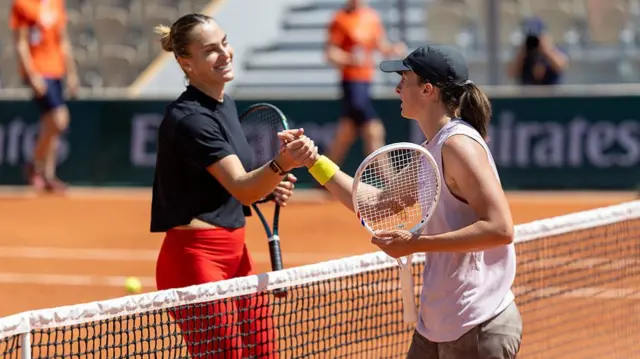 Aryna Sabalenka and Iga Swiatek shake hands after a practice session
