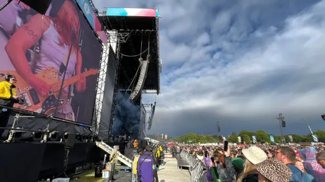 Wet Leg perform on the stage as crowds watch in Liverpool under some grey looking clouds