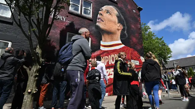Liverpool fans walk past a mural of Liverpool captain Virgil van Dijk before the Premier League match at Anfield, Liverpool.