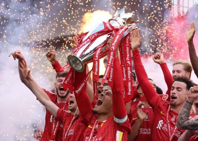 Liverpool's Virgil van Dijk lifts the trophy as he celebrates with teammates after winning the Premier League