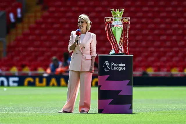 Kelly Cates standing next to the Premier League trophy at Anfield