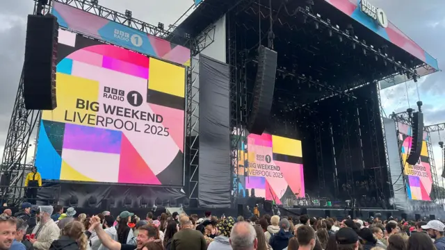 An empty main stage with a big crowd in front of it