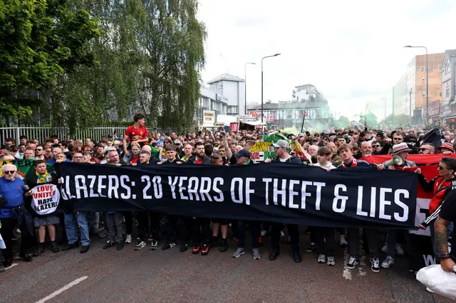 Fans of Manchester United protest with a banner reading "Glazers: 20 Years of Theft & Lies" outside the stadium prior to the Premier League match between Manchester United FC and Aston Villa FC at Old Trafford on May 25, 2025 in Manchester, England.