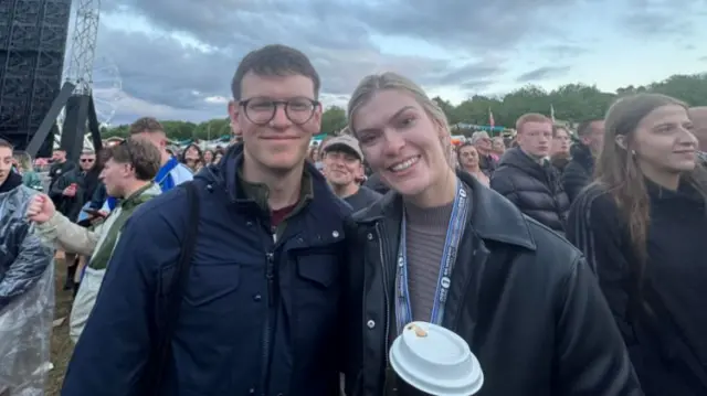 Niina and Dylan stood in crowd, stage behind them.