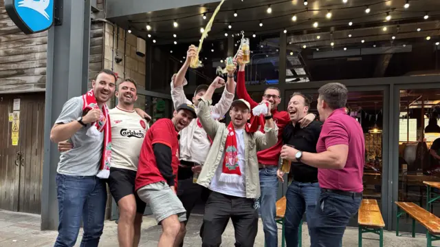 A group of Liverpool fans throws beer in the air