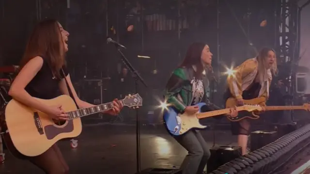 Haim strum guitars while performing on stage