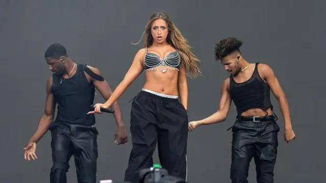 McRae dancing with one male dancer on either side of her also dancing
