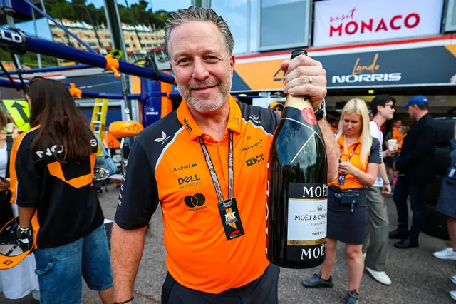 Zak Brown holding a champagne bottle