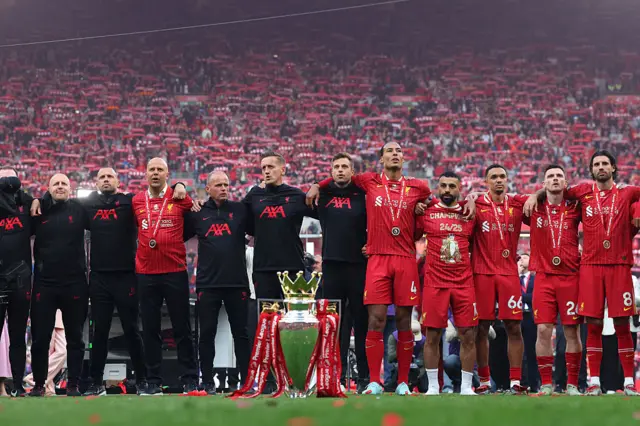 Arne Slot, Manager of Liverpool, and his coaching staff, sing You'll Never Walk Alone alongside Virgil van Dijk, Mohamed Salah, Trent Alexander-Arnold, Andrew Robertson and Dominik Szoboszlai of Liverpool, behind the Premier League trophy after the Premier League match between Liverpool FC and Crystal Palace FC at Anfield on May 25, 2025 in Liverpool, England.
