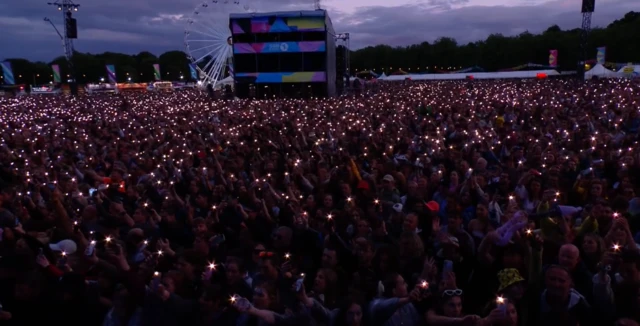 Swaying crowd holds up phone lights