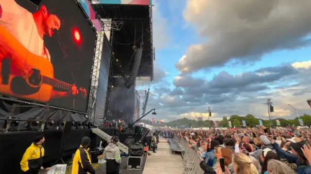 Crowd looking at stage, blue sky with some clouds.