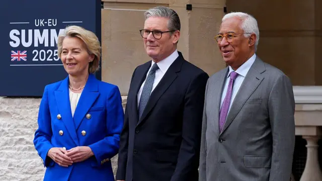 Ursula von der Leyen (L) in a bright blue double-breasted blazer and white blouse, Keir Starmer (C) in a black suit with patterned tie and Antonio Costa (R) in a grey suit with deep pink tie pose for pictures outside Lancaster house