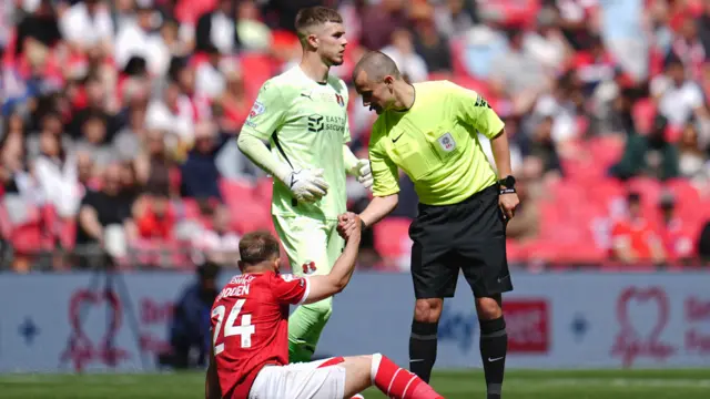 Referee Andrew Kitchen helps Matthew Godden of Charlton Athletic to his feet