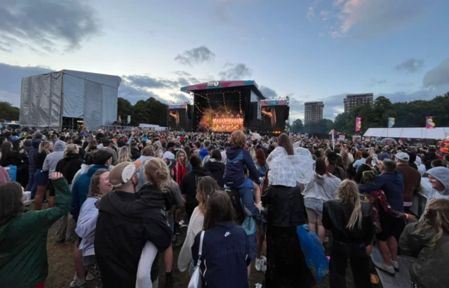 Families hold up children in the crowd watching Mumford & Sons