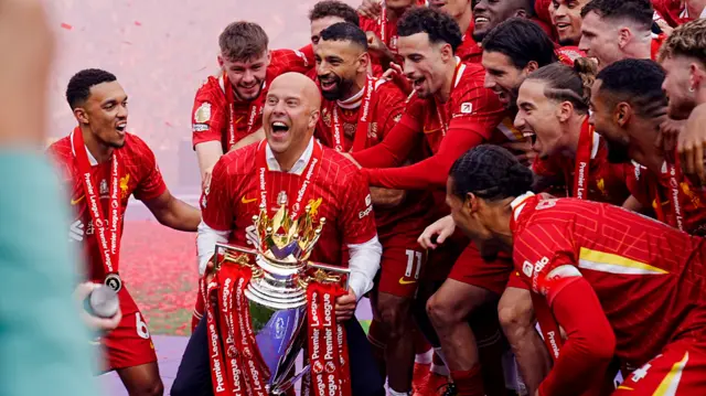 Arne Slot celebrates winning the Premier League, grabbing hold of the trophy
