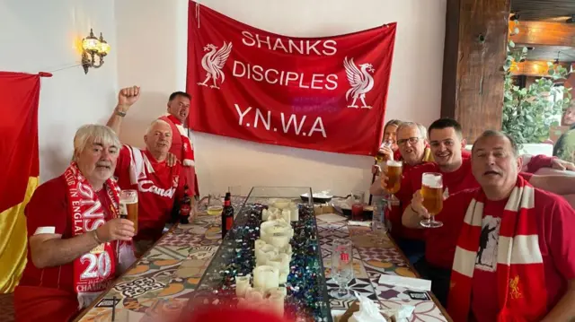 Seven Liverpool fans sat around a table drinking beers