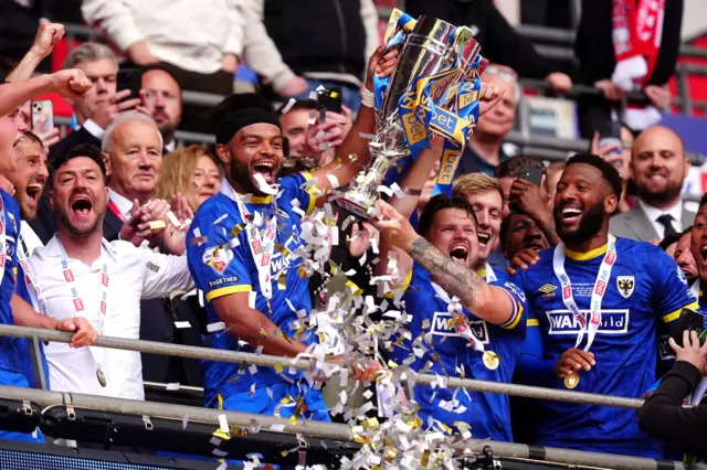 Wimbledon players lift the League Two play-off final trophy