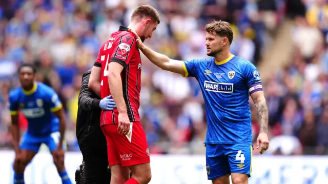 Walsall's Harry Williams is consoled by AFC Wimbledon's Jake Reeves (right) after being helped off the pitch due to an injury