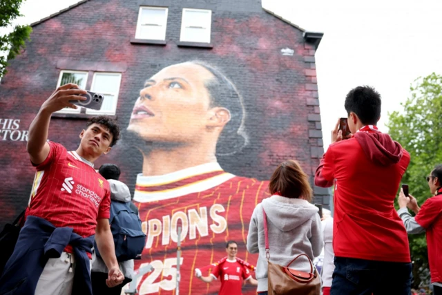 Fans take selfies next to a mural of the club's captain Virgil Van Dijk