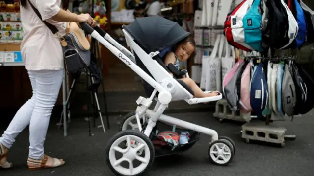 A woman pushing her baby in a stroller shops in the Hongdae area of Seoul, South Korea, June 29, 2016
