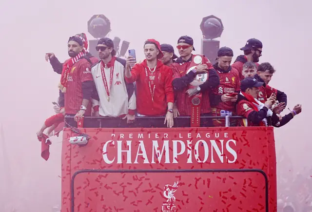 Liverpool players on top of a bus surrounded by red smoke