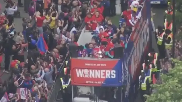 The trophy at the front of a bus in a crowd