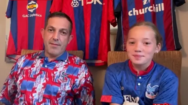 A man and young girl sitting next to each other with Palace shirts on and three hanging behind them