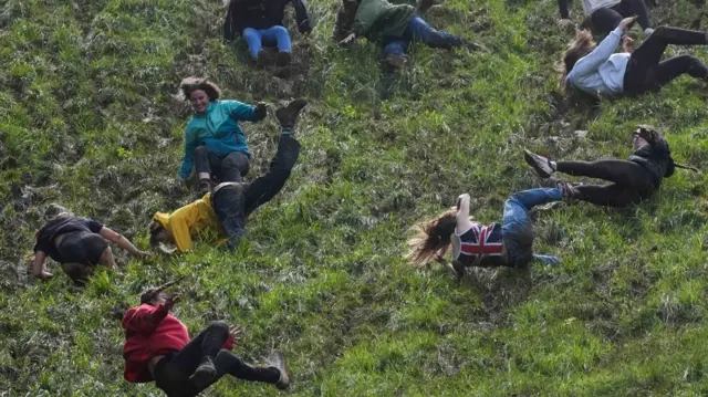 Contestants in the Gloucestershire cheese rolling event tumble down Cooper's Hill