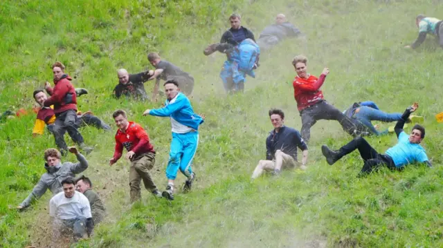 Several competitors tumble down a dusty Cooper's Hill during the Gloucestershire cheese rolling event