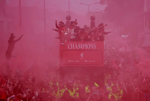 Liverpool players on top of a bus surrounded by red smoke
