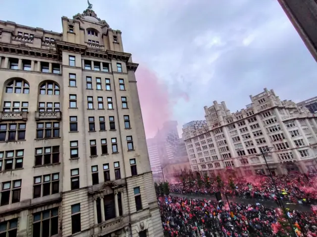 Liver Building with crowd of people in front and red smoke