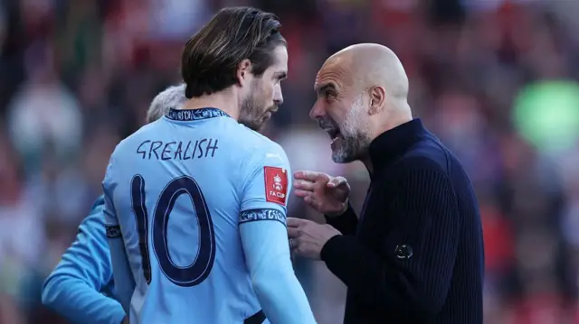 Pep Guardiola speaks with Jack Grealish