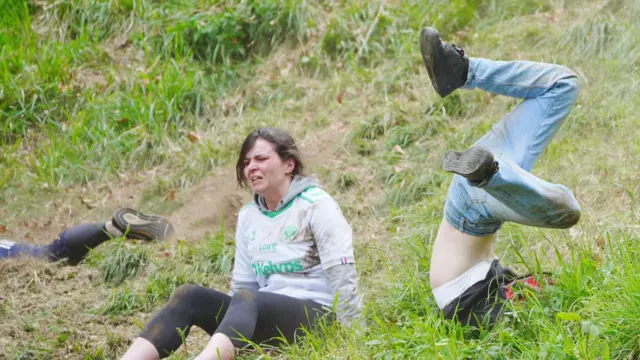Two women tumble down Cooper's Hill as part of the Gloucestershire cheese rolling races