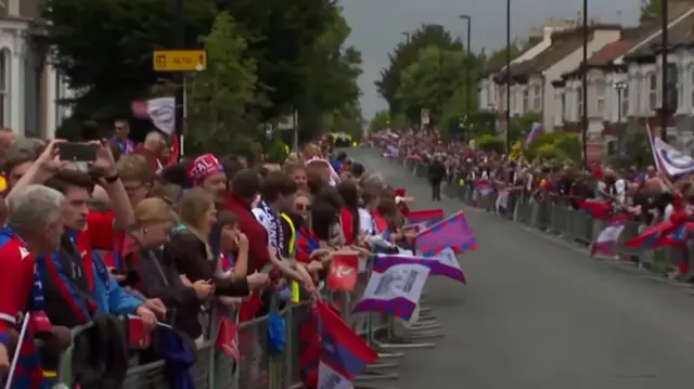 A street lined with crowds and an empty street in the middle